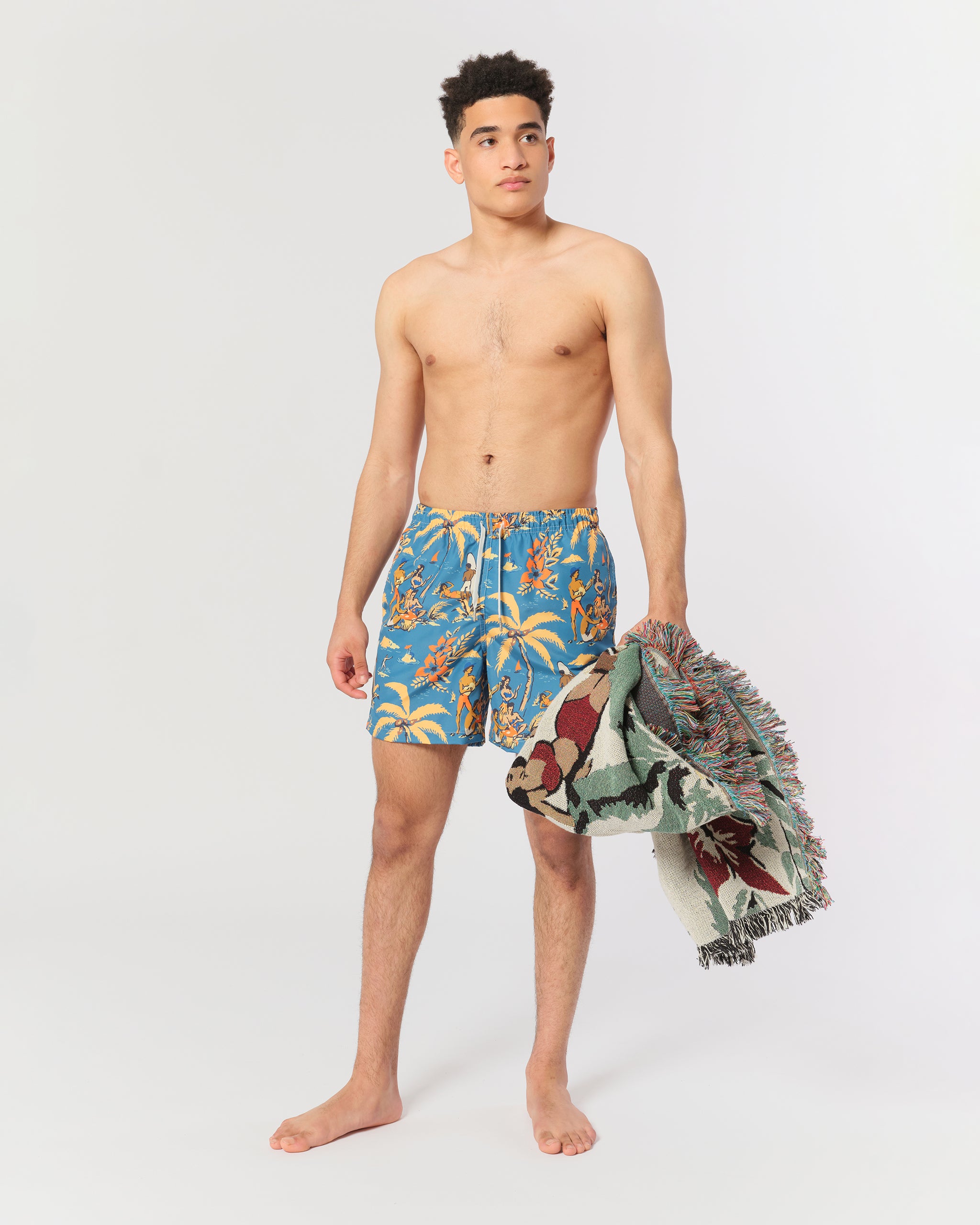 Blue swim trunk with Hawaiian-inspired printed beach scene shot on model