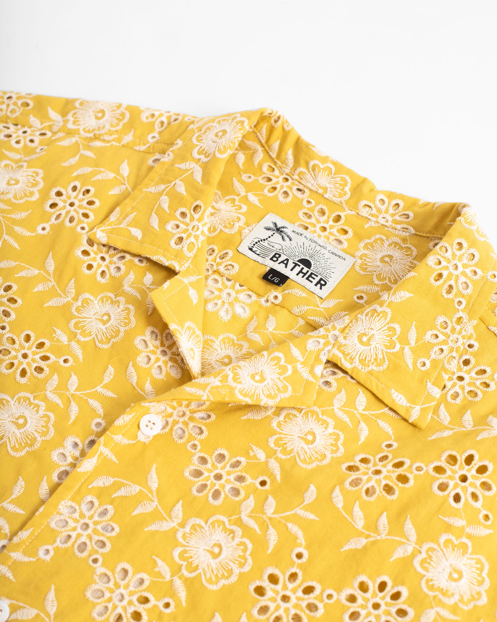 Collar close up of Yellow camp shirt with an embroidered floral pattern