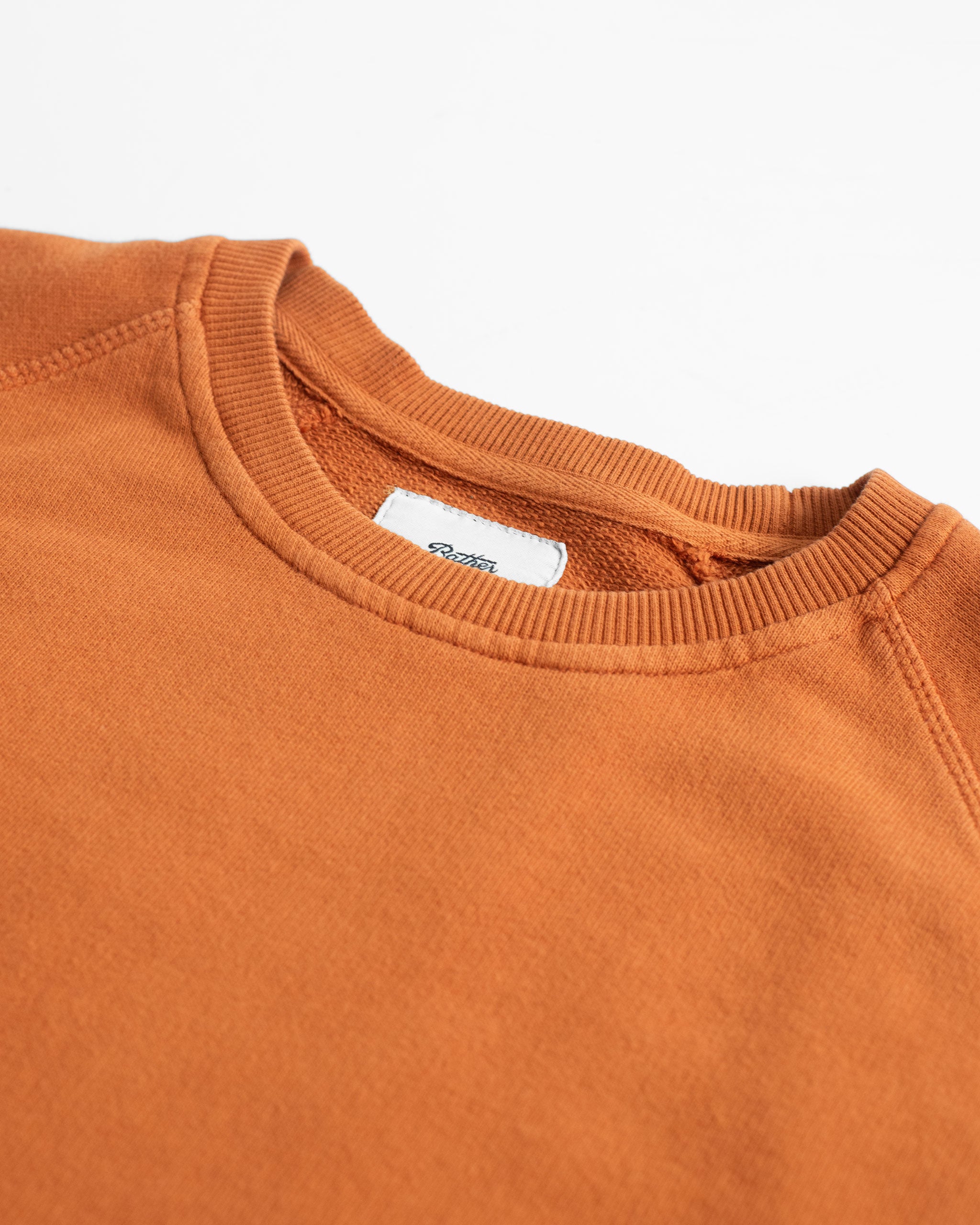 Collar close up shot of Orange french terry raglan sleeve crewneck sweatshirt