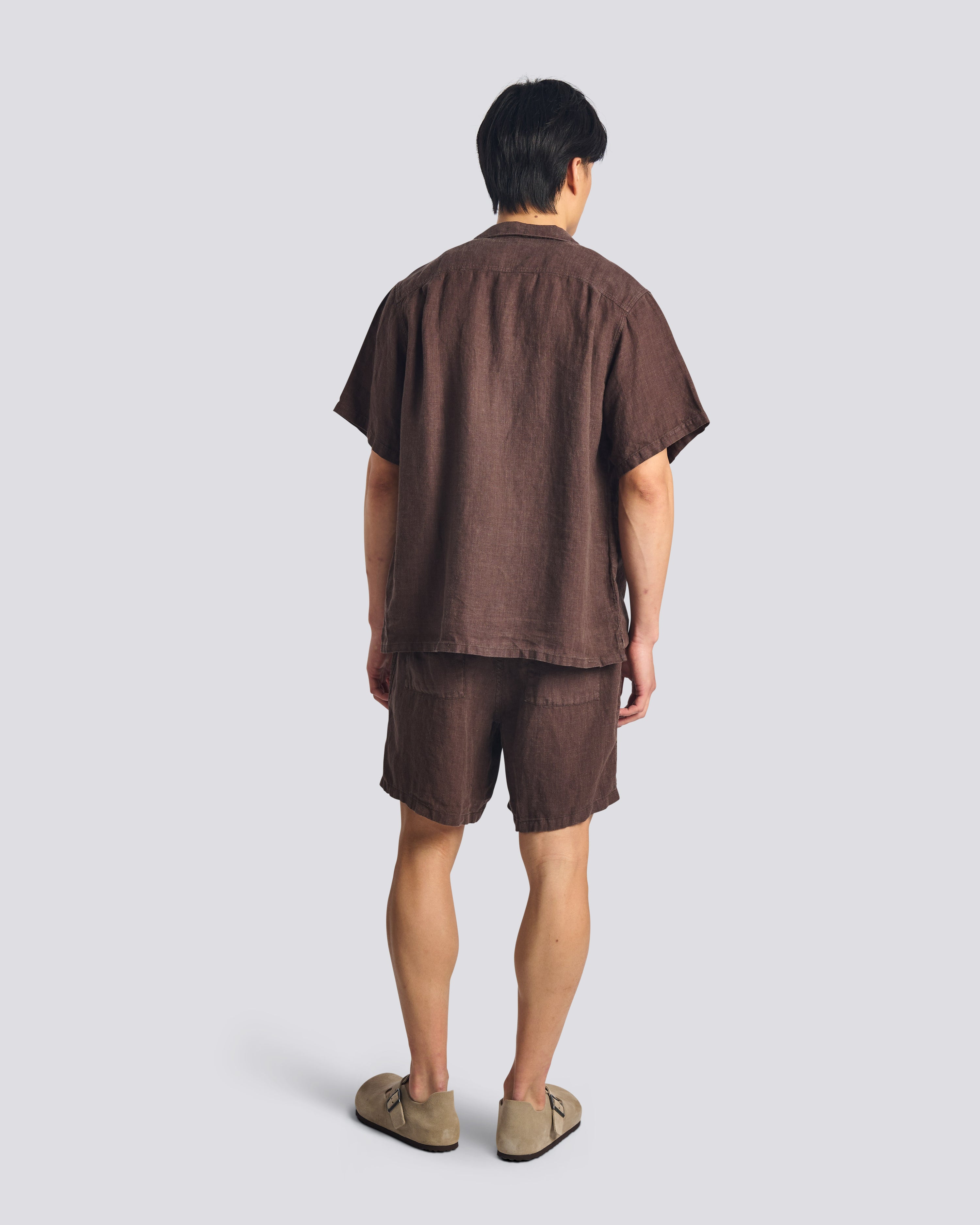 Back view of model wearing Bather men's dark brown linen drawstring shorts