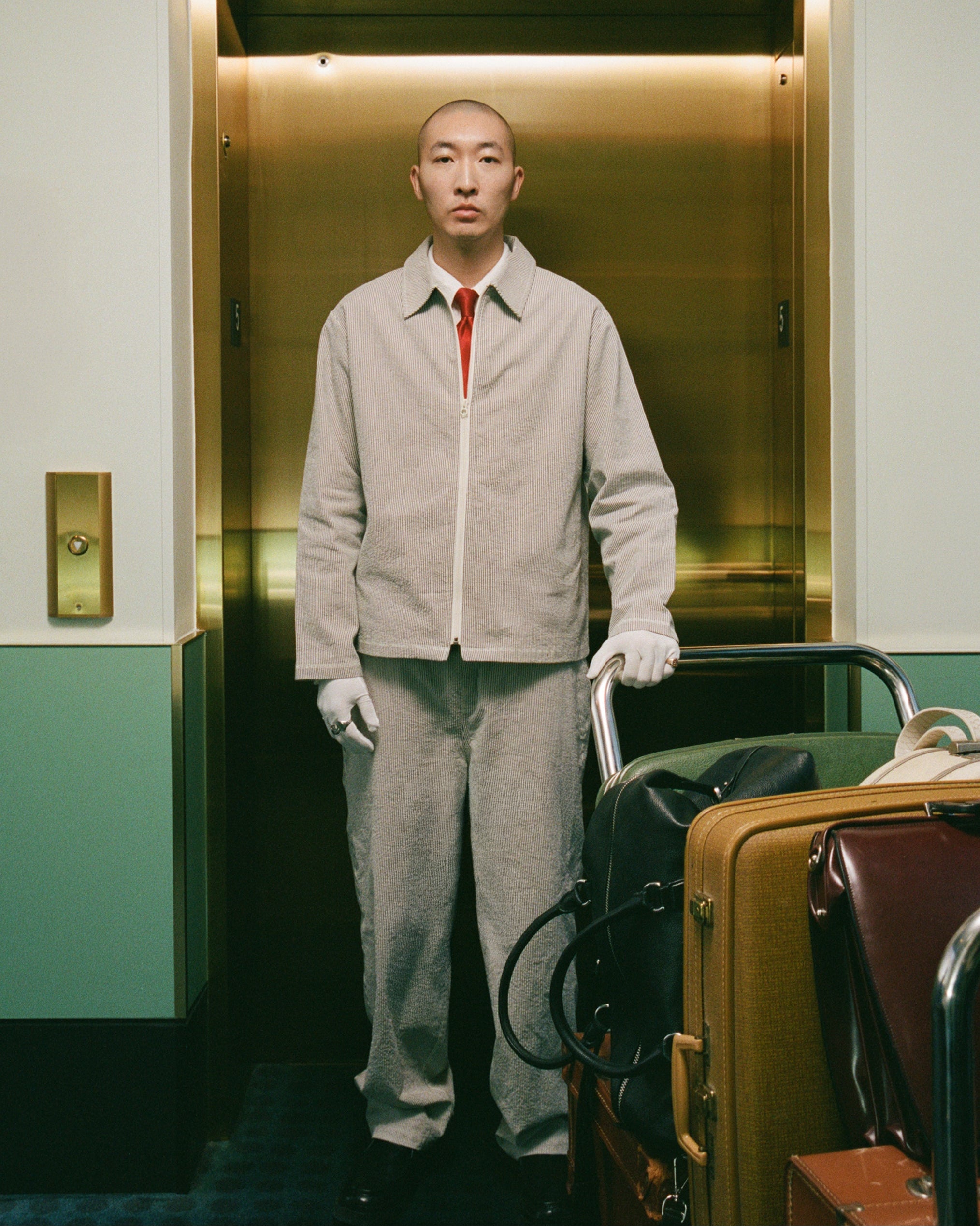 Bather editorial shoot of model wearing brown pinstripe tour jacket and leisure pant