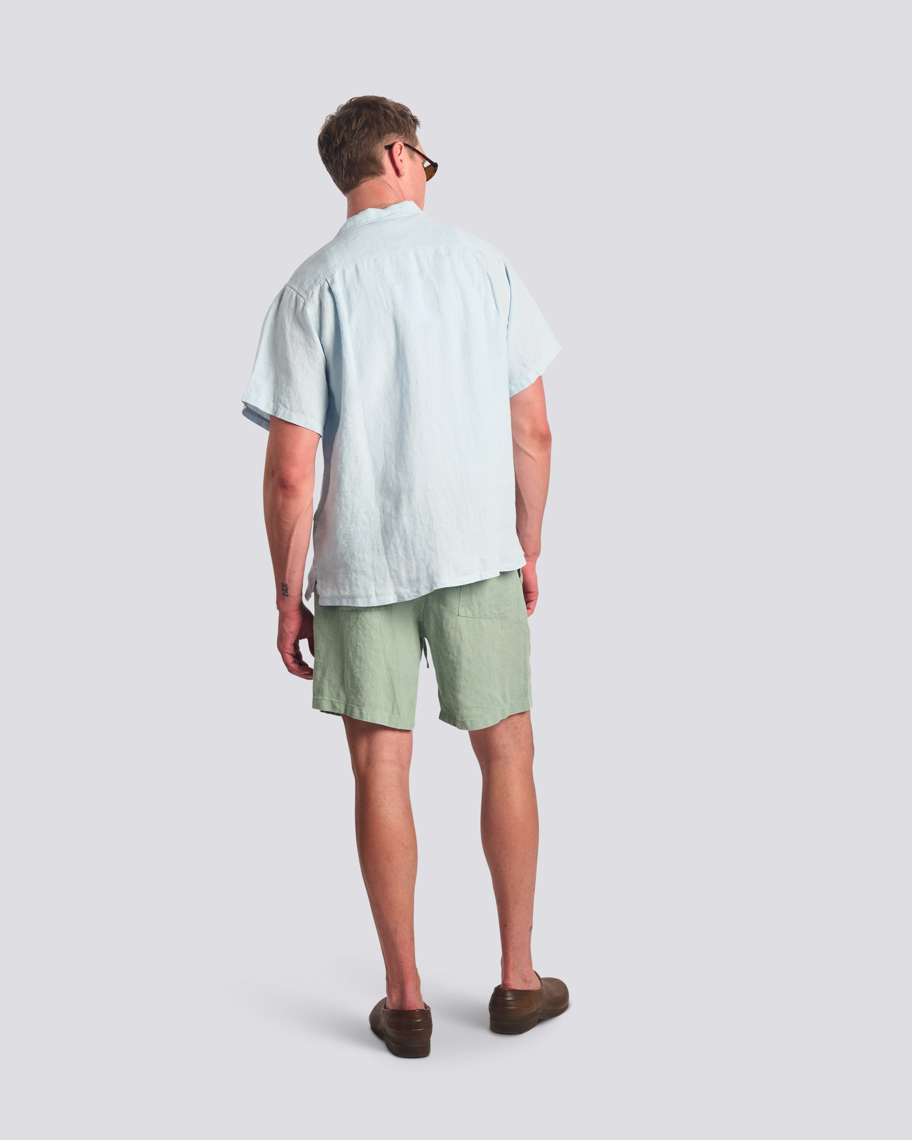 Back view of model wearing Bather men's light green linen drawstring shorts