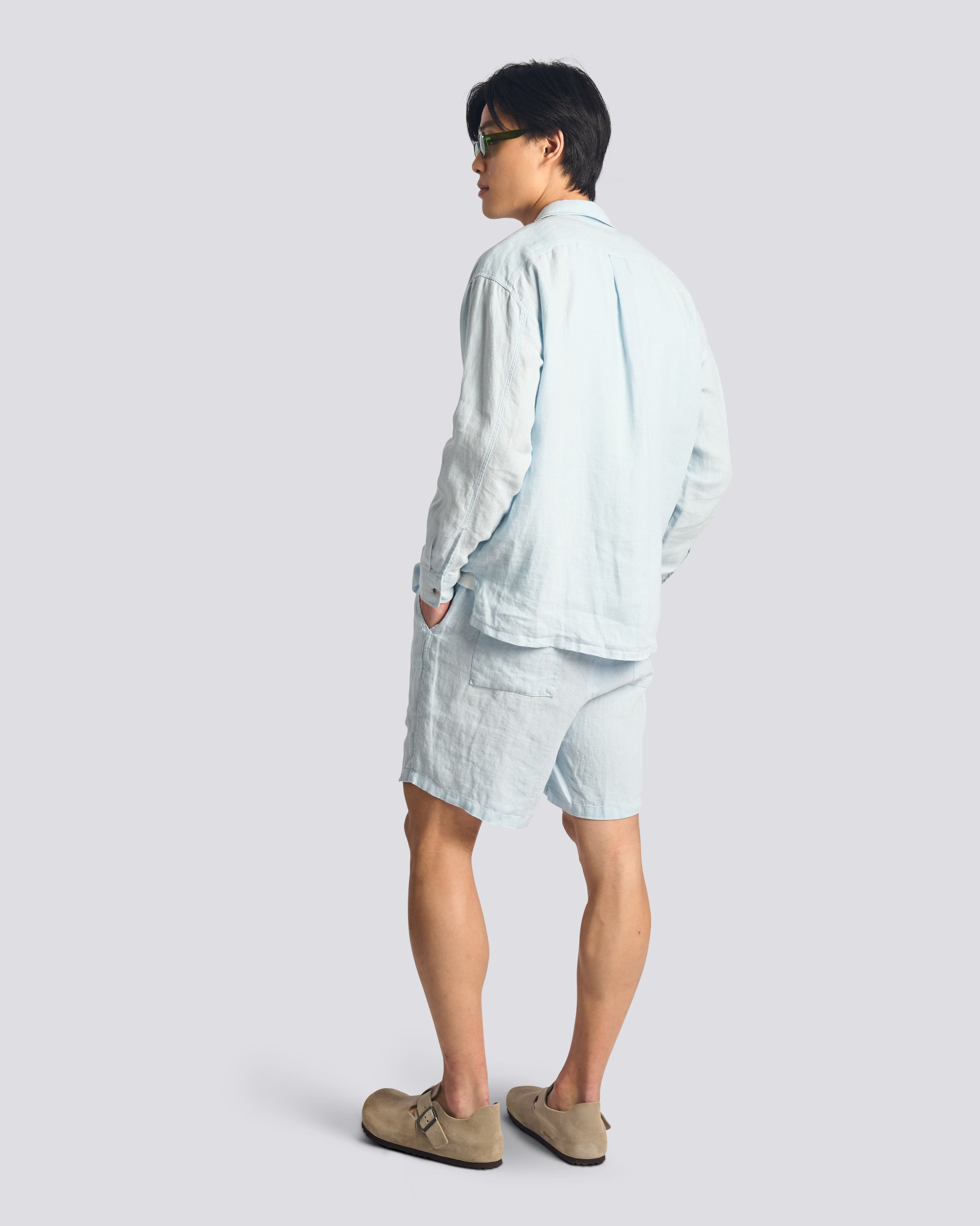 Back view of model wearing Bather men's light blue linen drawstring shorts