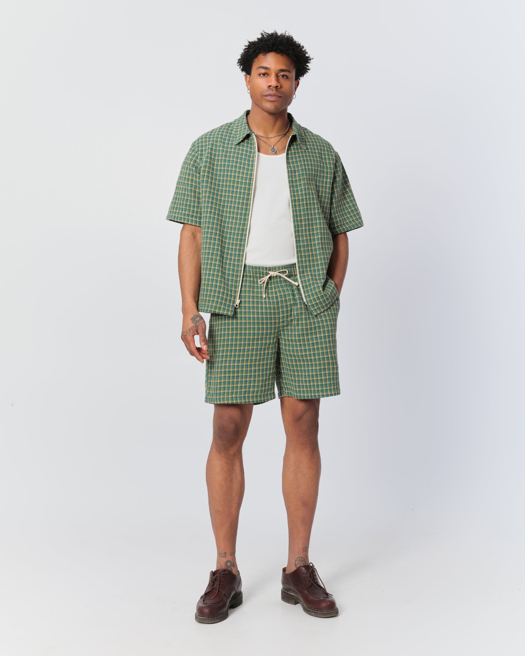 Model wearing Bather men's green and yellow check drawstring shorts with a matching zip-up polo