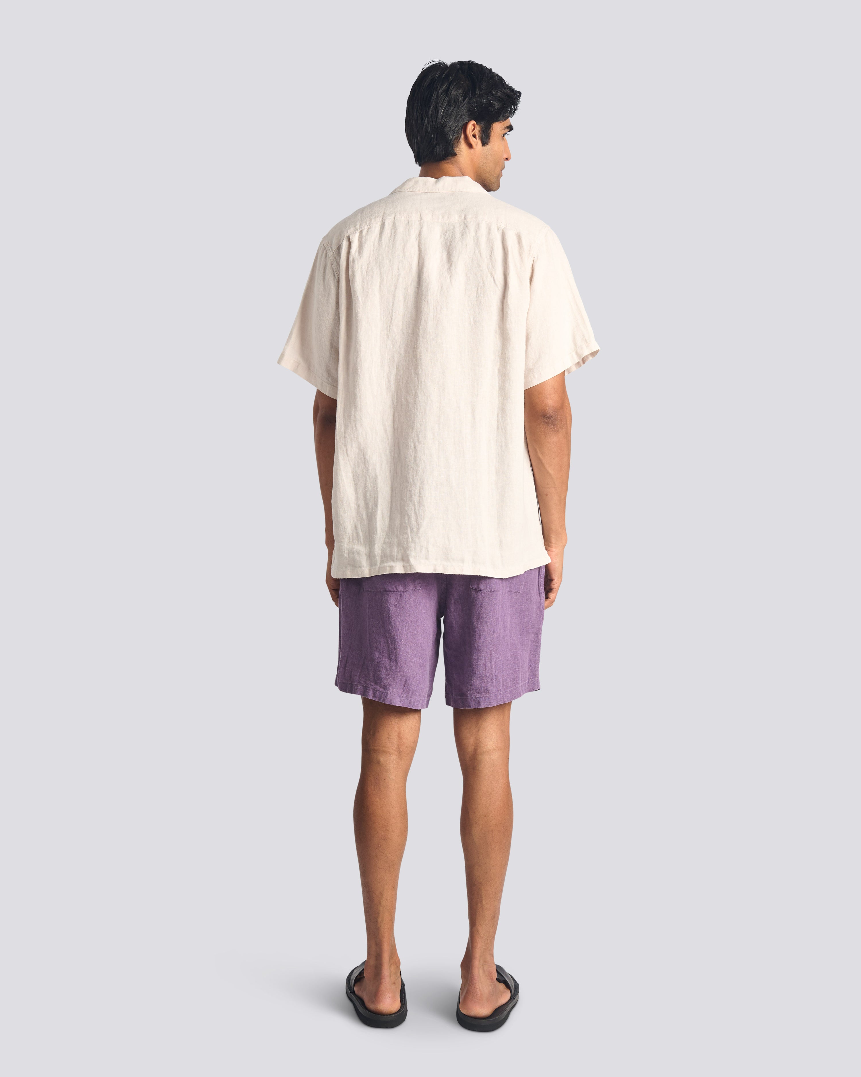 Back view of model wearing Bather men's purple linen drawstring shorts