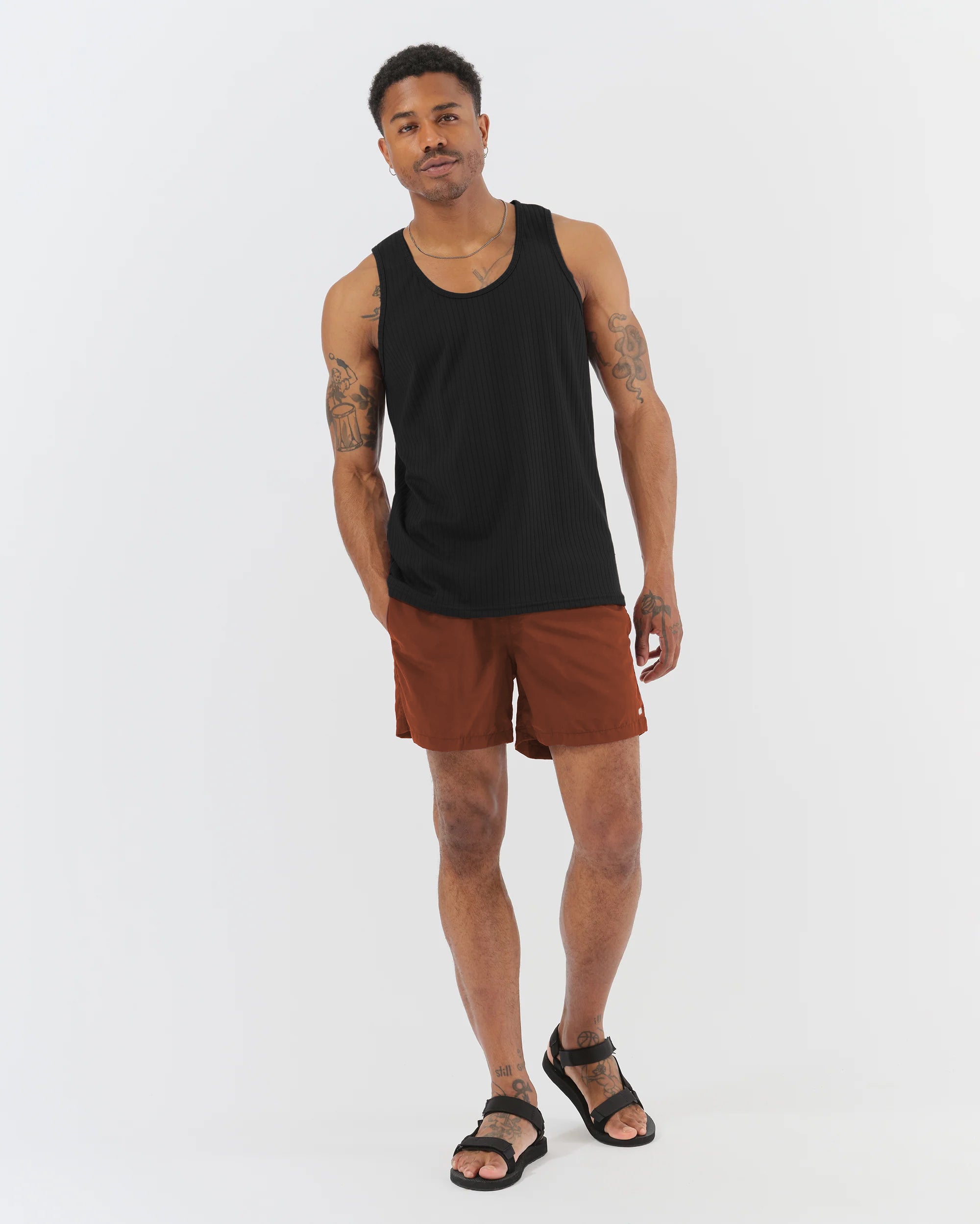 Man wearing a black tank top and brown shorts on a white background