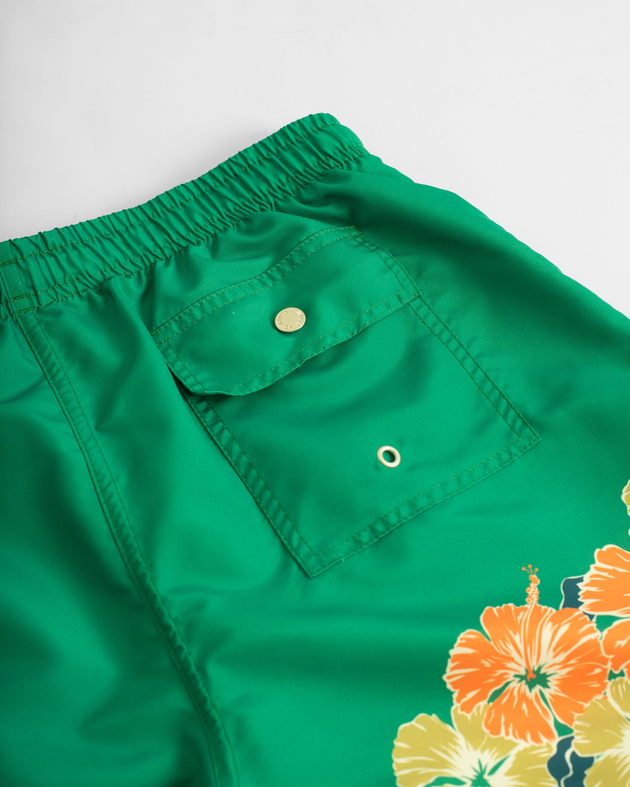 Back Pocket Close Up of Green swim trunk with floral motif pattern on the bottom of the leg
