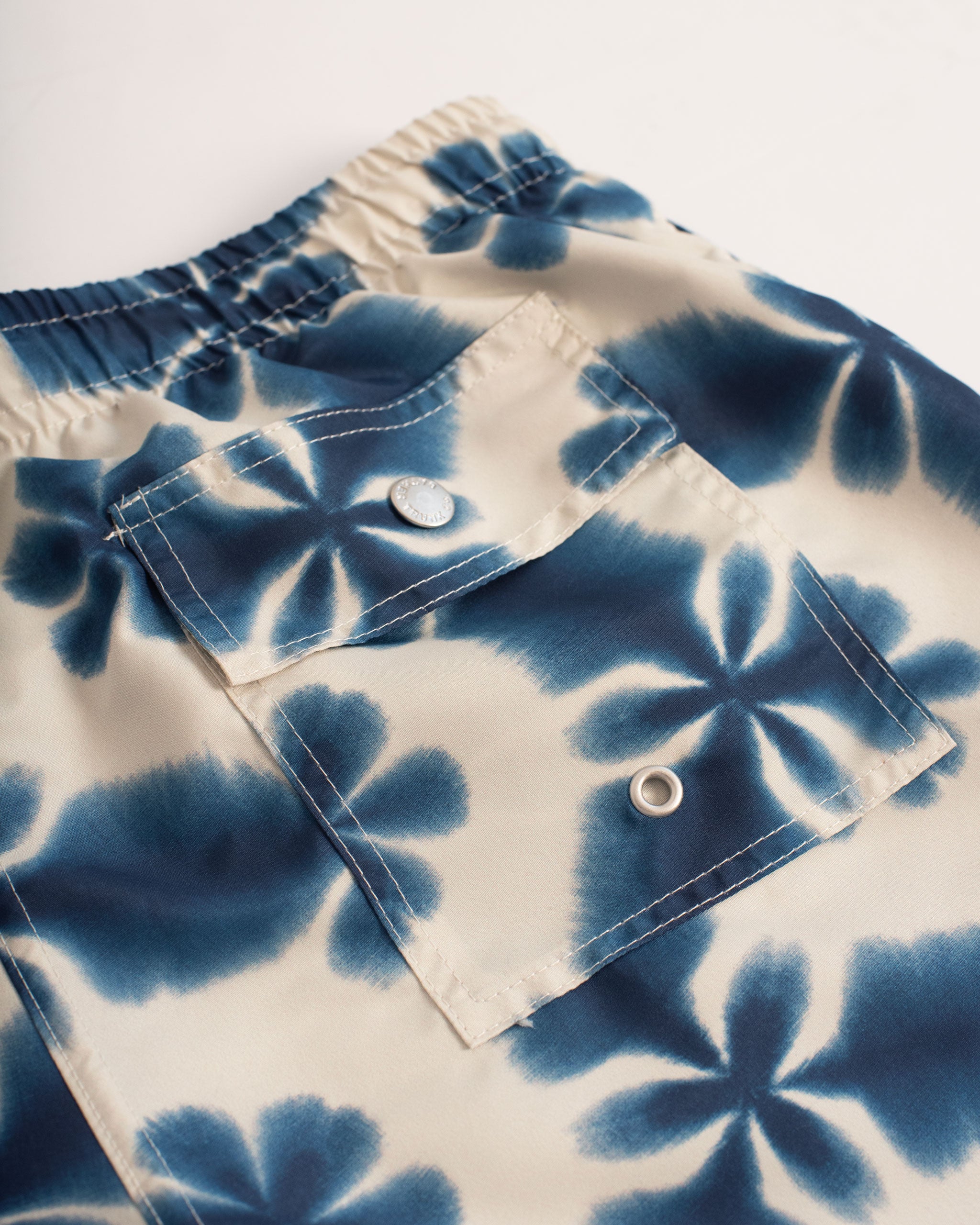 Back pocket shot of A navy swim trunk with a shibori-inspired print, similar to a kaleidoscope pattern