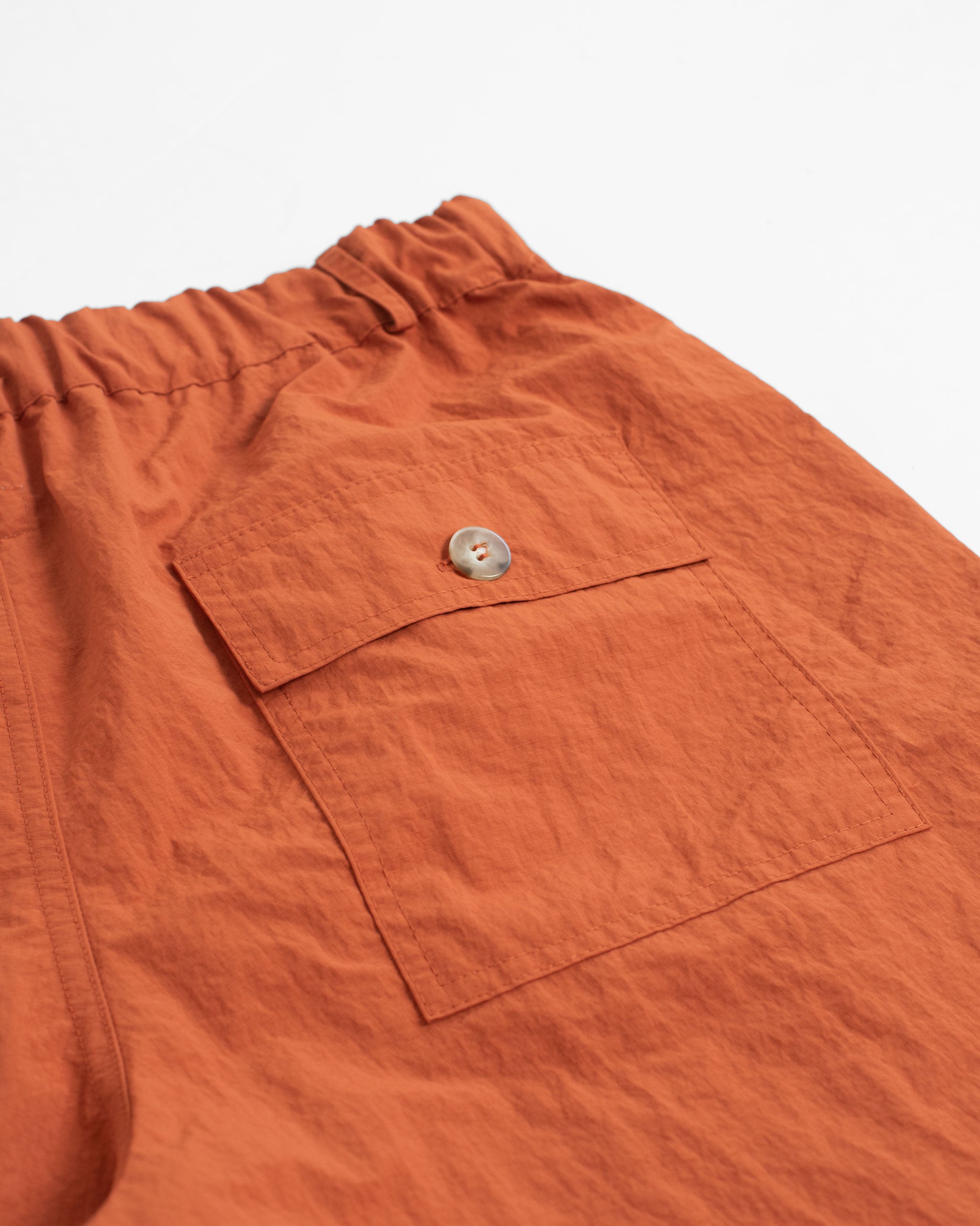 Back pocket close up of Solid Orange nylon utility shorts