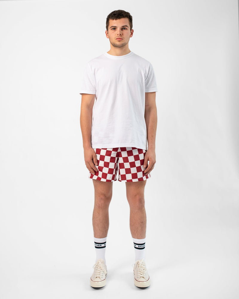 Model wearing Bather swim trunk with red and white checkerboard pattern